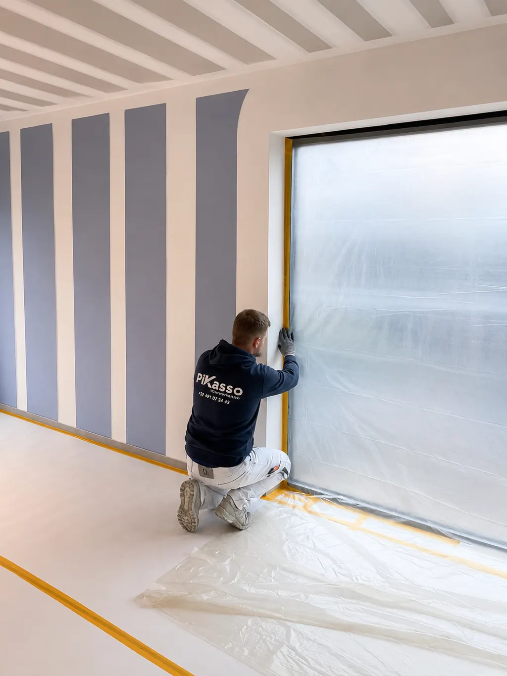 Schilderwerken voor aannemers: schilder van Pikasso werkt een plafond af op een nieuwbouwwerf